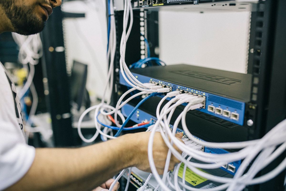 Hands patching cables into a network switch in a rack